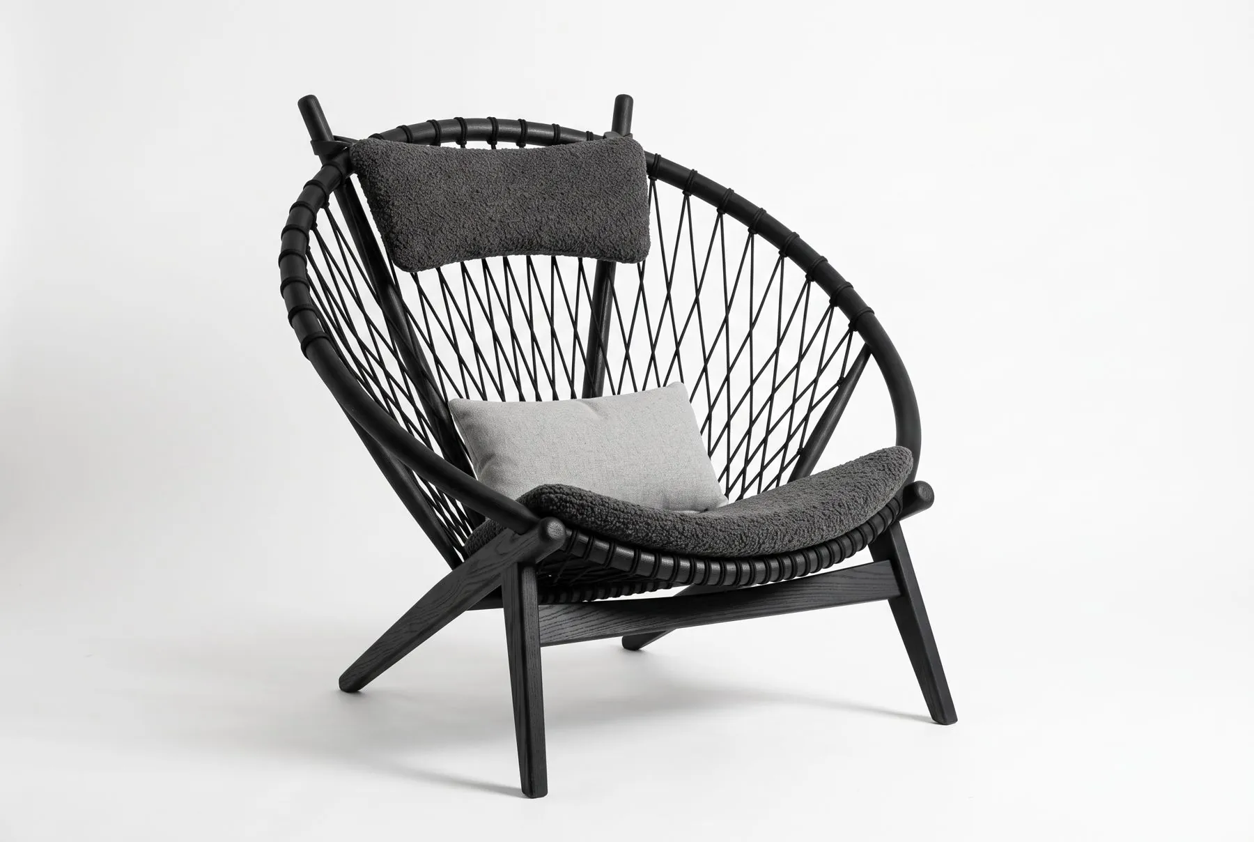 Black wood lounge chair with graphite cushions, studio shot