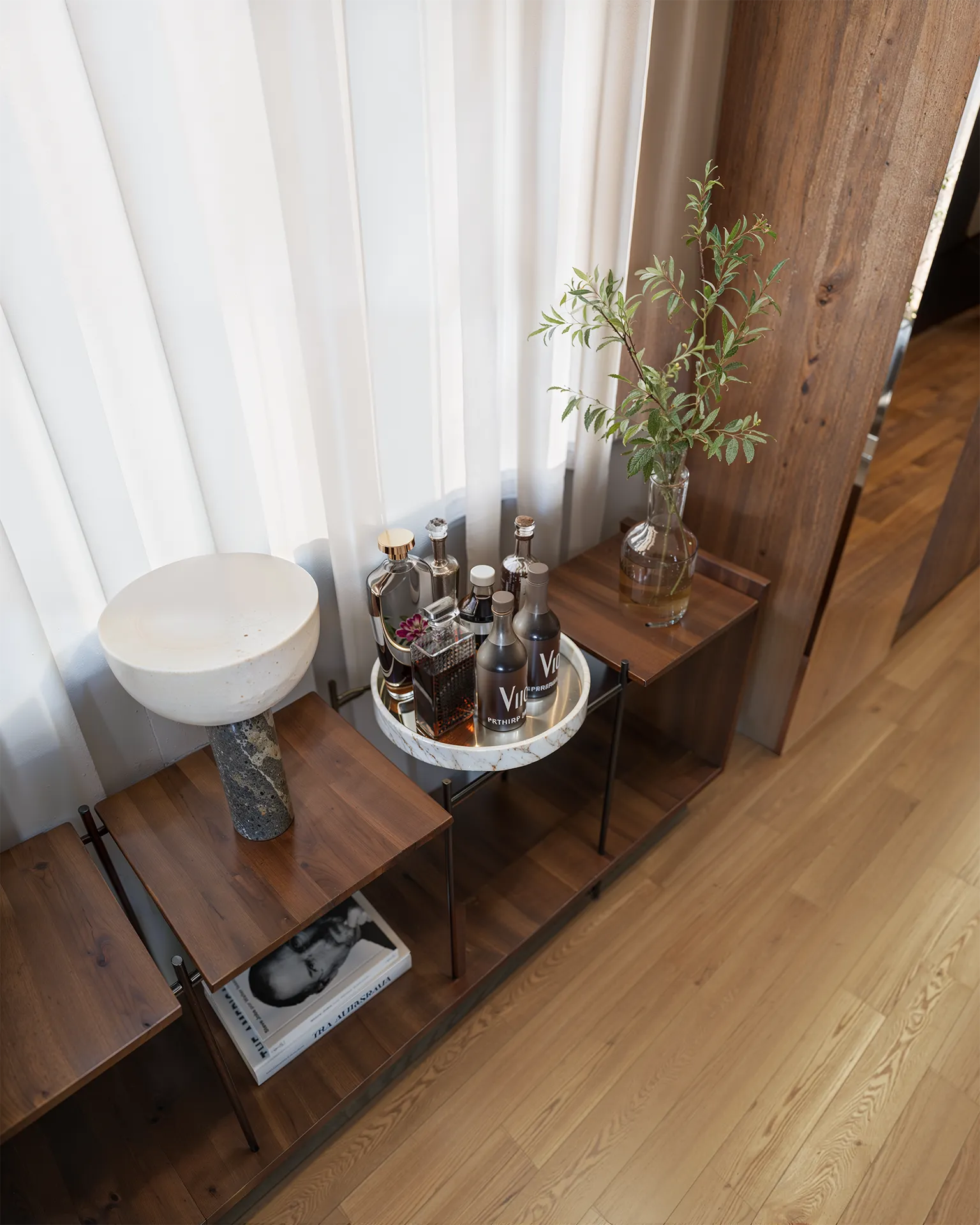 Detalhe do salão de festas do Liv Green Residence com bandeja de bebidas, vaso com galhos e luminária de pedra em render 3D