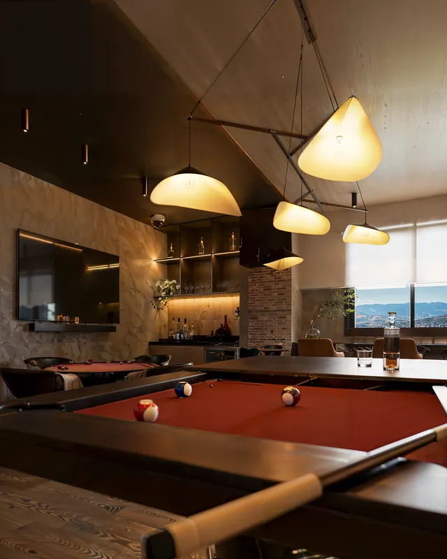 Render 3D de la sala de juegos Liv Green con techo inclinado, lámparas de tela y billar de tapete rojo